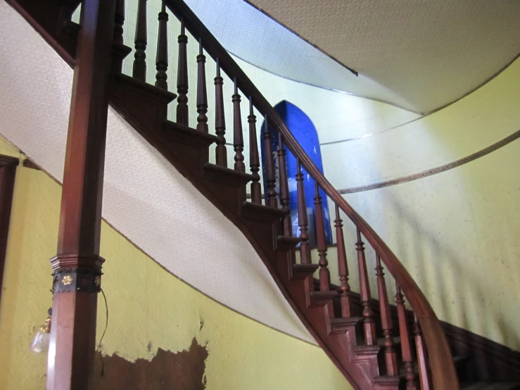 an iron hand rail stands near a stair case in the corner of a room