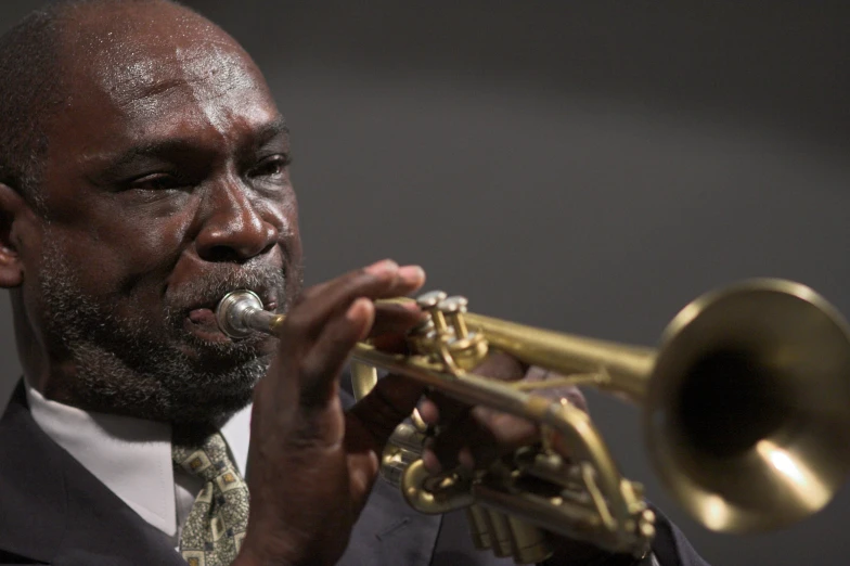 a man with dark skin and a suit playing a ss trumpet