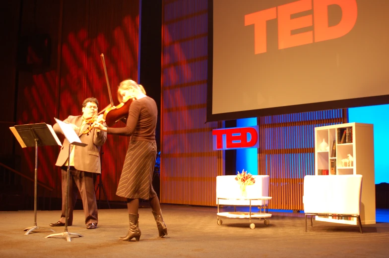 two women are playing violin on stage at ted's