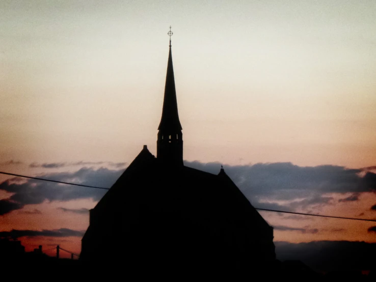 a church steeple with the sun setting behind it