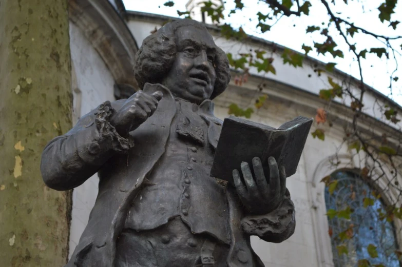 a statue of a man holding a book with his hand