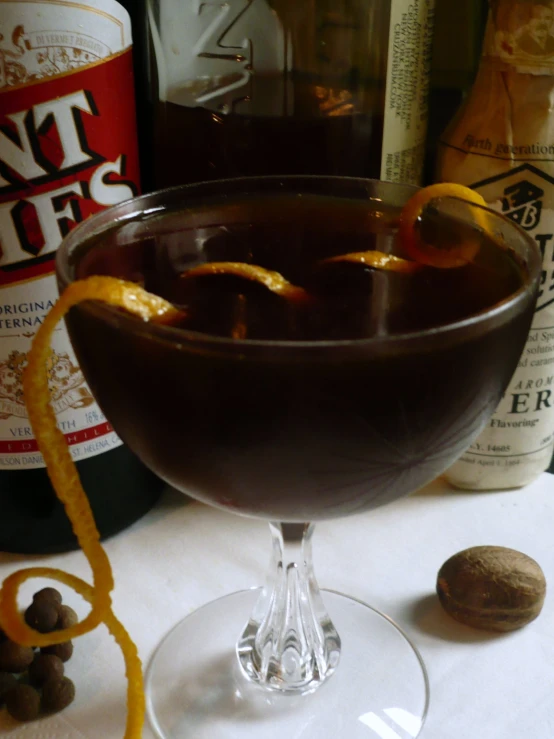 a dark drink with orange peels and nuts