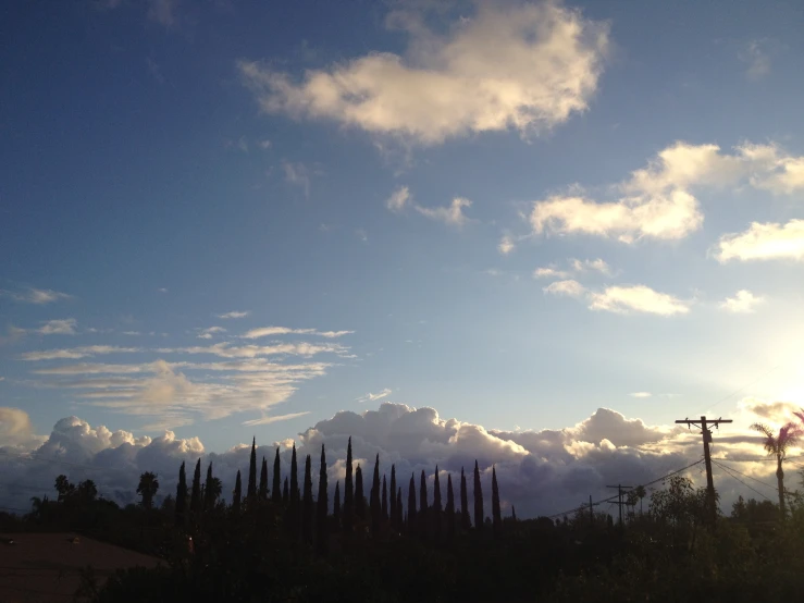 the sky is filled with clouds and some trees