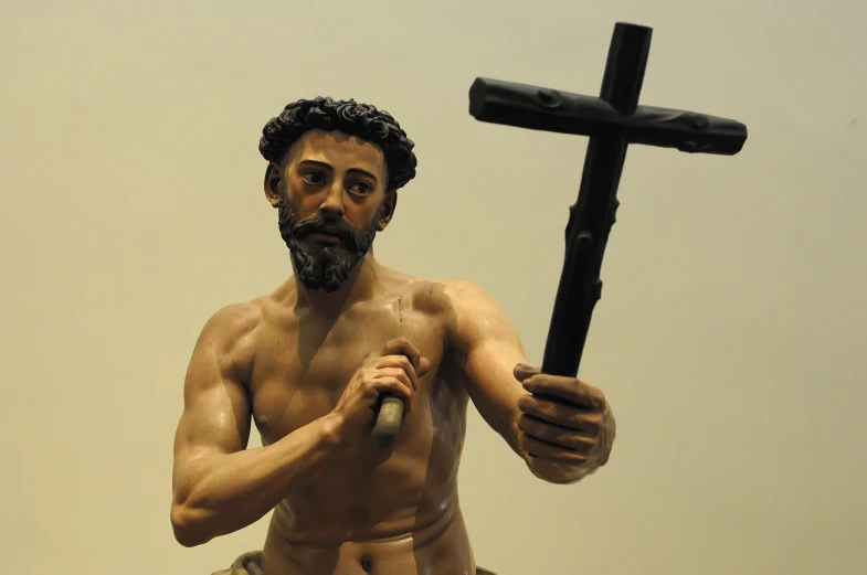 a statue of jesus holding a crucifix with one arm in the other