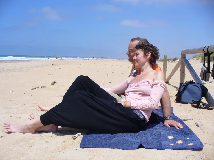 a man and woman sitting on the beach