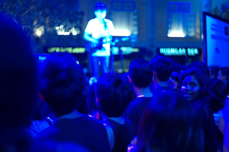 people watching a man on stage in a crowded area