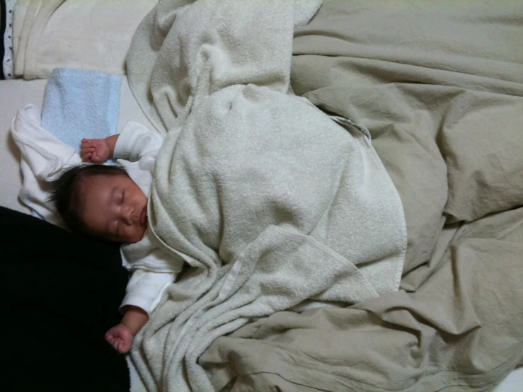 a baby wrapped in blankets sleeping on a bed