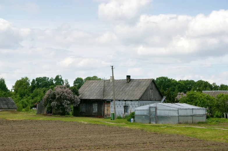 a farm and house set against a sky filled with clouds