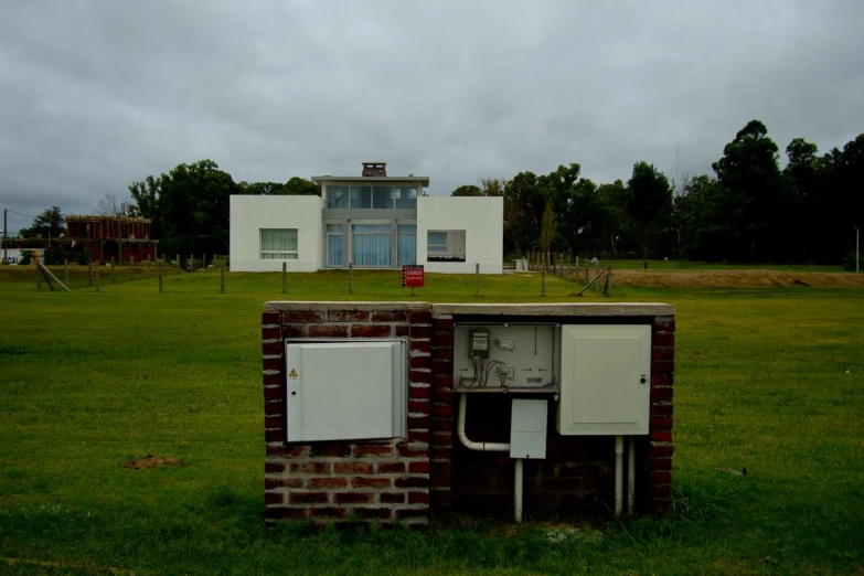 a brick box with two electrical plugs sitting in a field