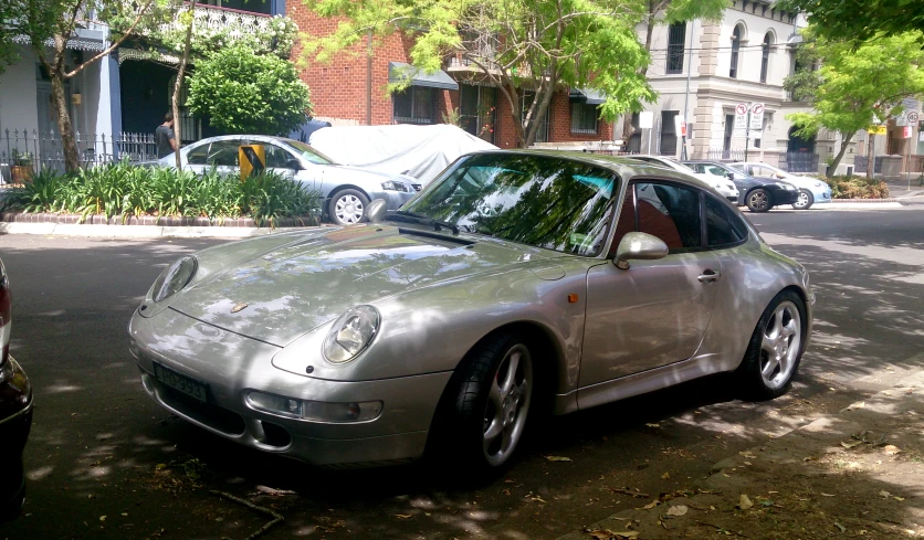 a silver sports car parked on a tree covered street