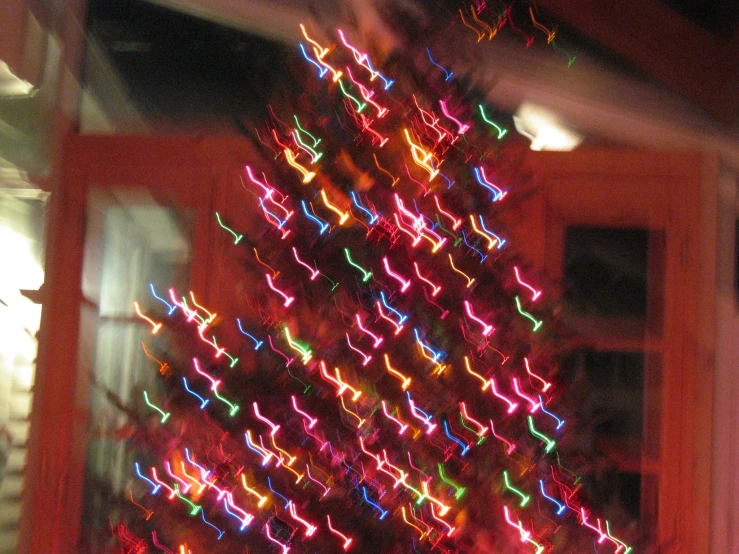 a multi colored christmas tree next to a front door