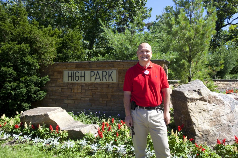 man standing next to a brick sign for high park