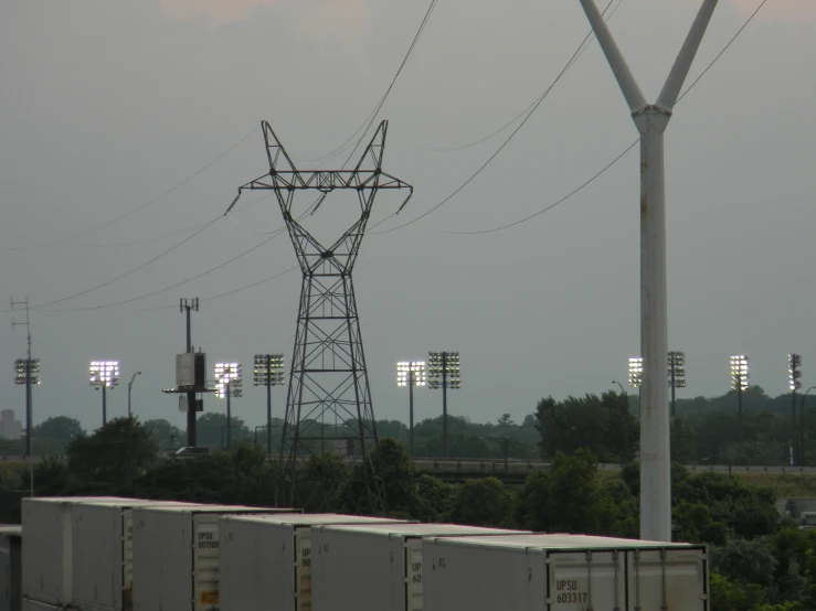 the electrical tower is next to a long train