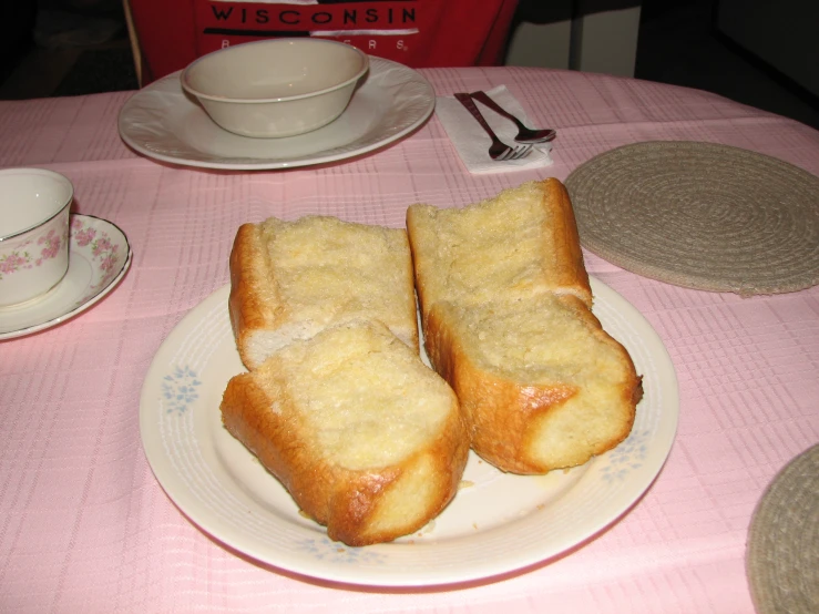 bread sticks are sitting on a plate beside coffee cups