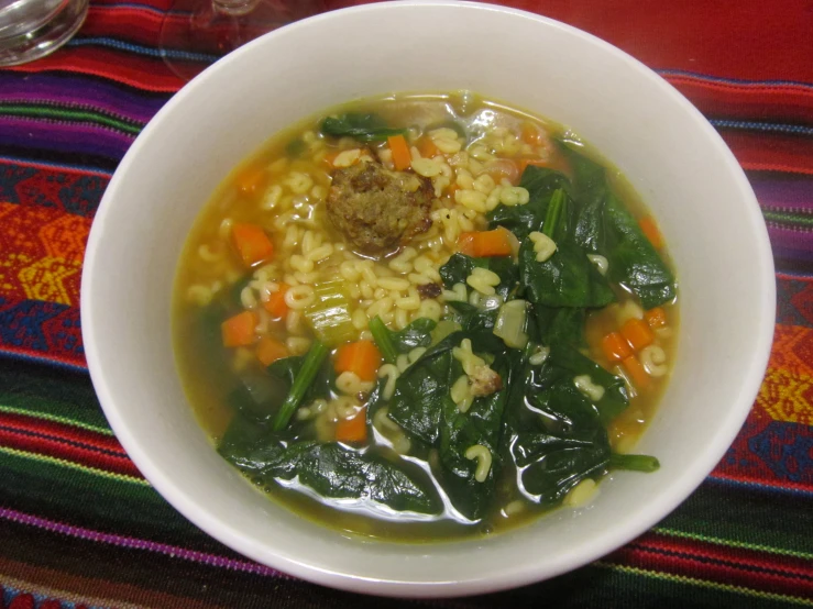 this soup is served in a bowl with noodles and spinach