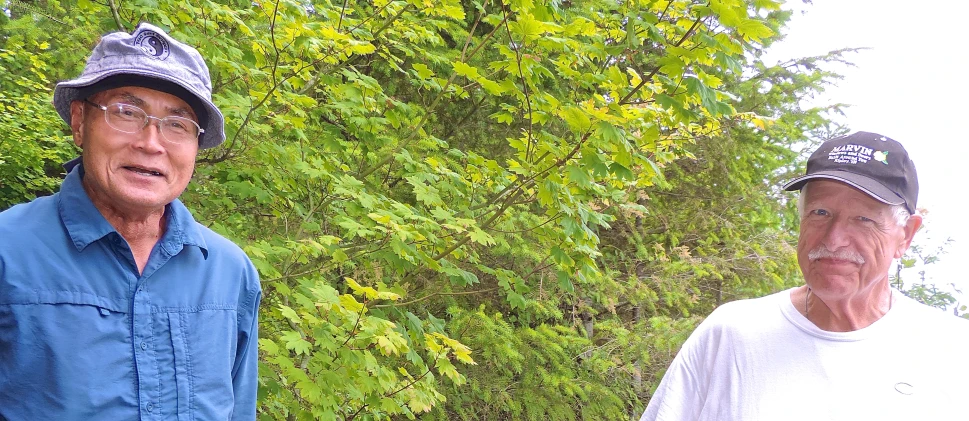 two old men standing in front of trees