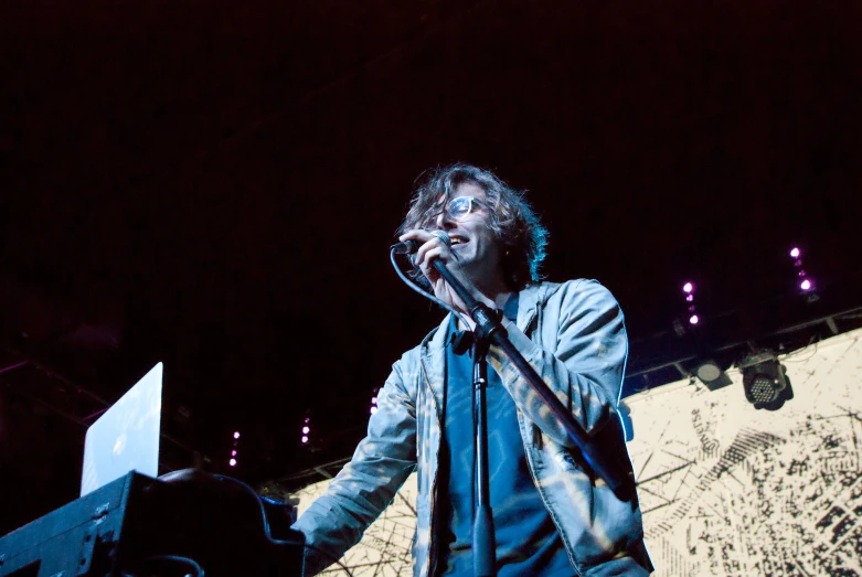 a man singing into a microphone with the lights on in the background