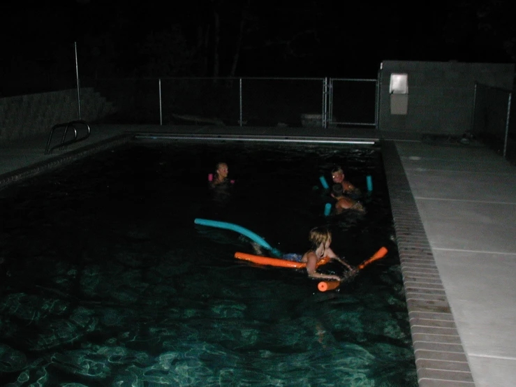 a group of s playing with a paddle in an outdoor swimming pool