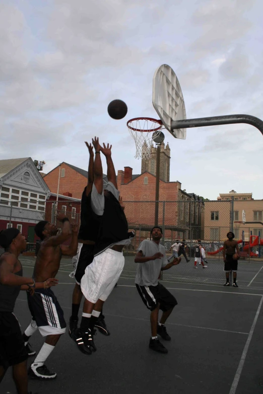 men playing basketball on an outdoor court with buildings in the background