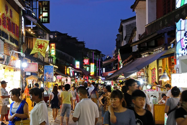 a crowded street filled with people walking at night