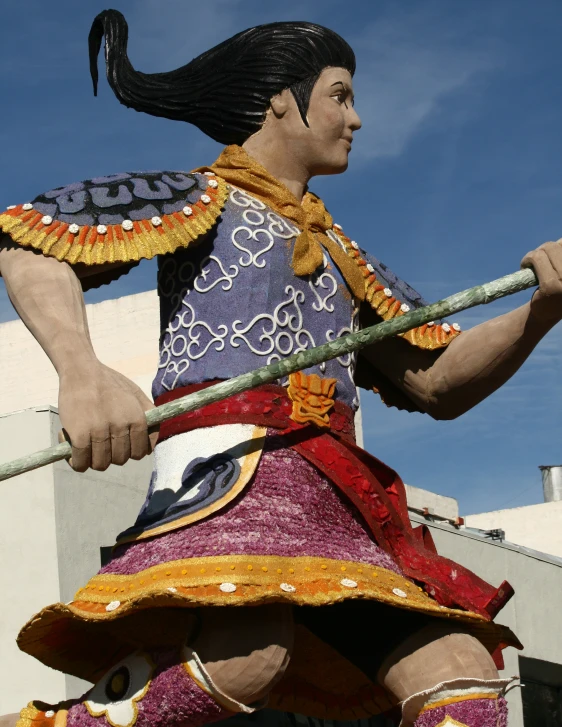 the statue depicts an oriental warrior carrying a stick