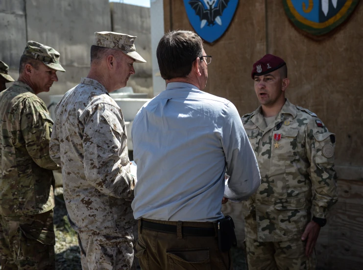 three soldiers and one man in uniform talking