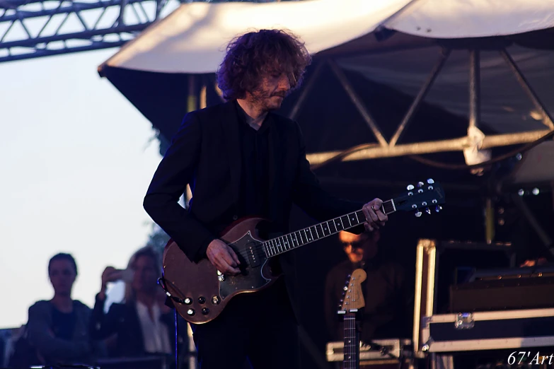 the man is playing his guitar in front of an umbrella