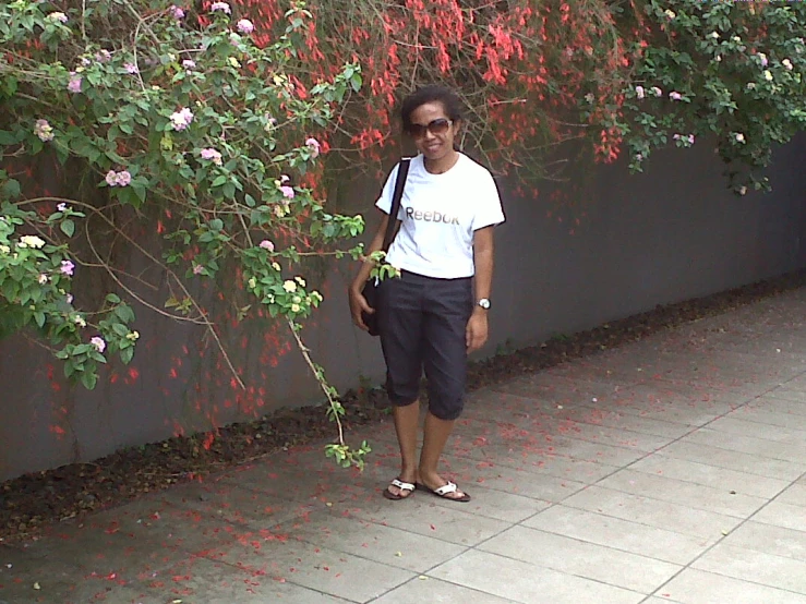 a woman stands against a wall and looks at her camera