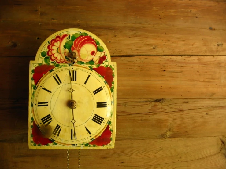 an old clock is decorated with fish on a red and yellow surface