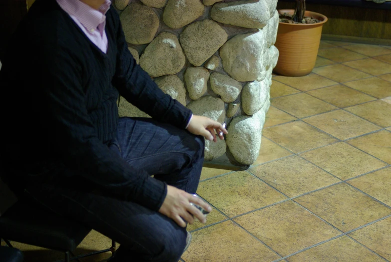 a woman sitting down by some big rocks