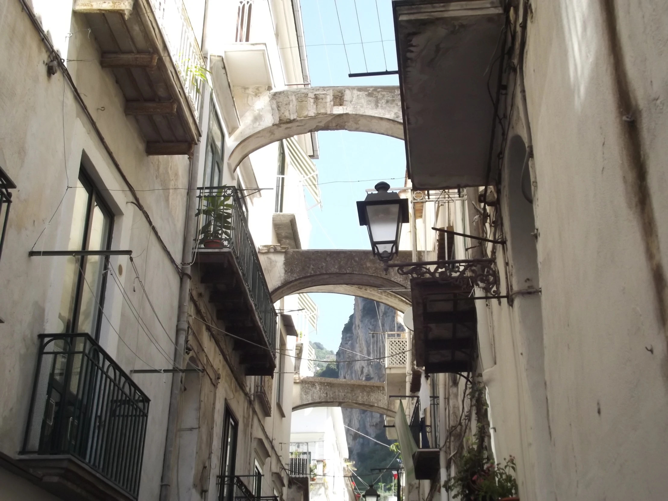 narrow alley way in city with stone arches and lanterns