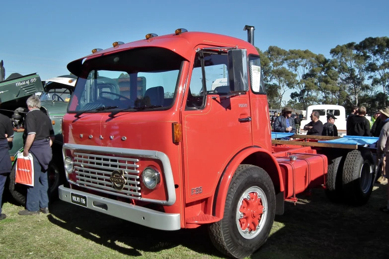 a red truck parked next to other vehicles at a truck show