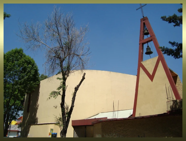 the bells and roof of a church by the tree