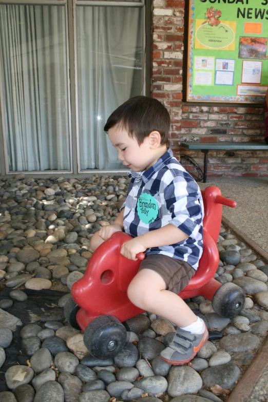 the small boy is sitting on a toy car