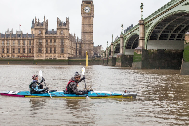 two people in the water with a clock tower in the background