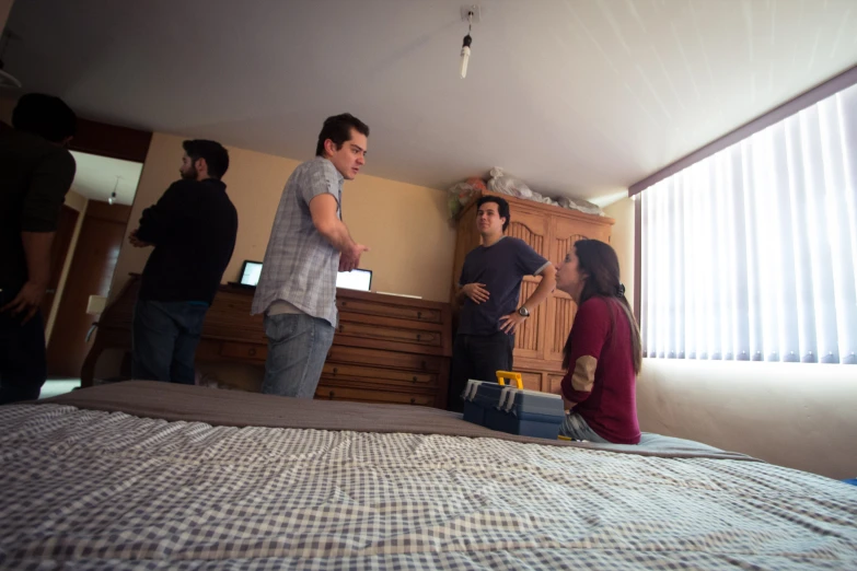 several people are standing around a bedroom by the window