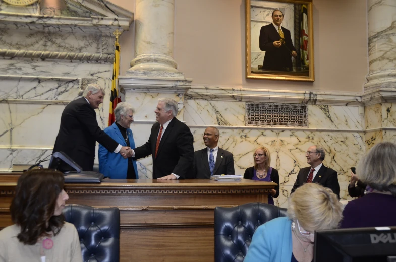 two men and one woman shaking hands at a table