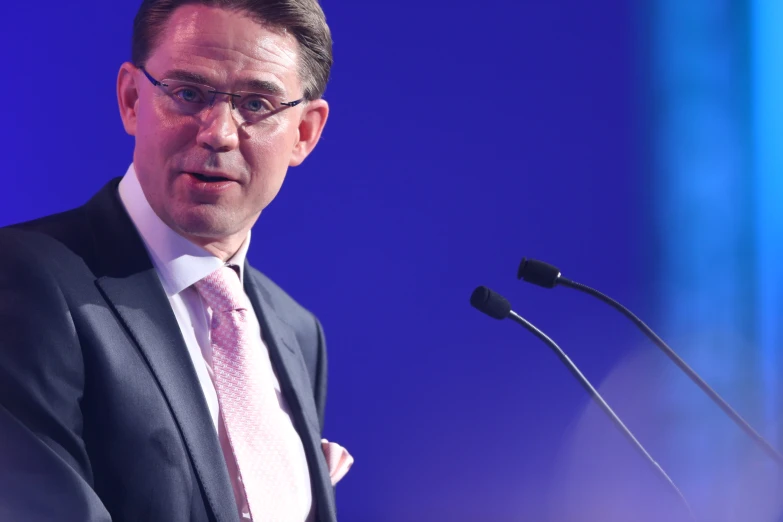 a man with glasses speaking at a podium