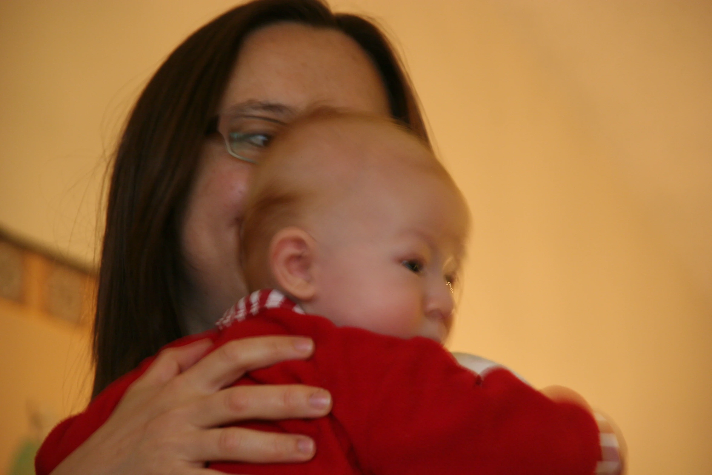 a woman holding a baby wearing a red sweater