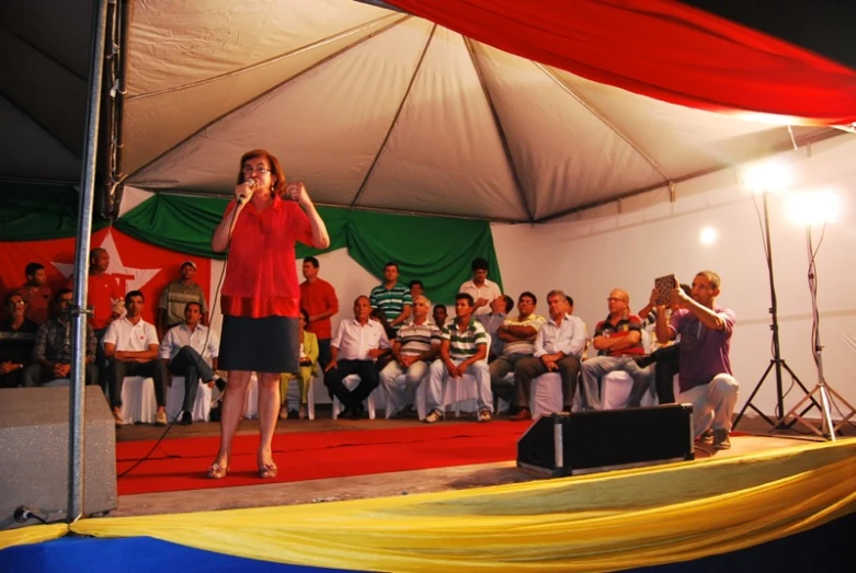 a woman standing on a stage and speaking to the crowd