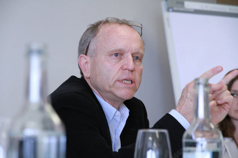 a man sitting in front of a whiteboard holding a marker