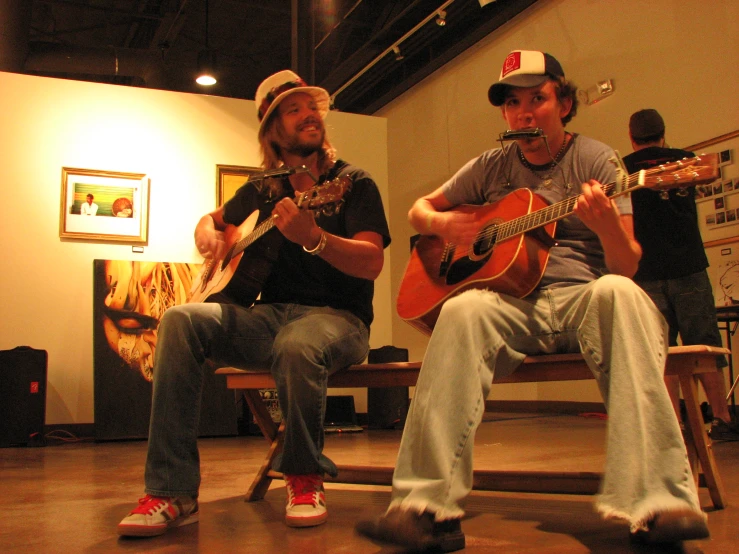 two people sitting in a room with guitars