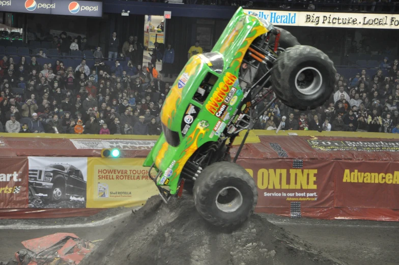 a monster truck flipping a dirt pile in a stadium