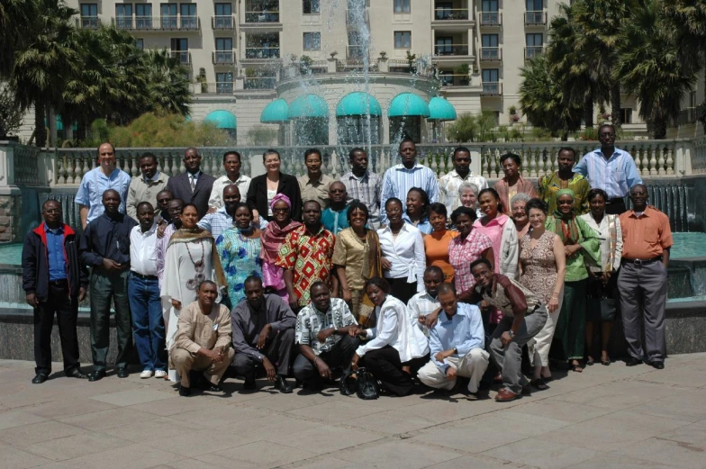 many people are smiling together in front of a fountain