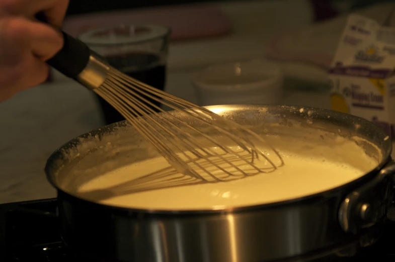 a person whisking food in a pot on the stove