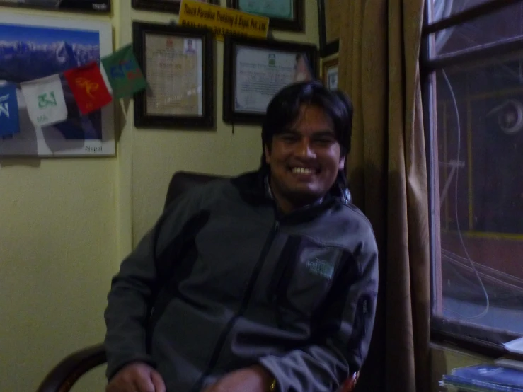 a man smiles as he sits in his office