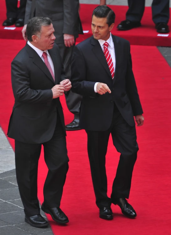 two men in suits on a red carpet