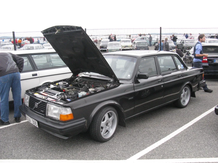 a black car with an open hood in a parking lot