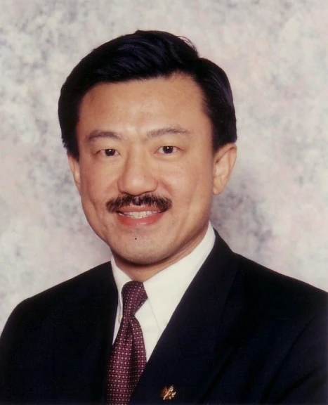 an older male in a suit and tie smiling