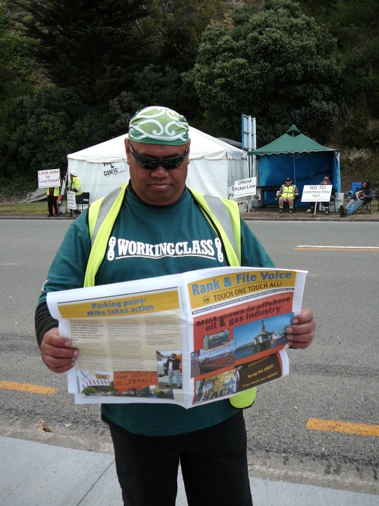 a man stands on a street while reading a newspaper